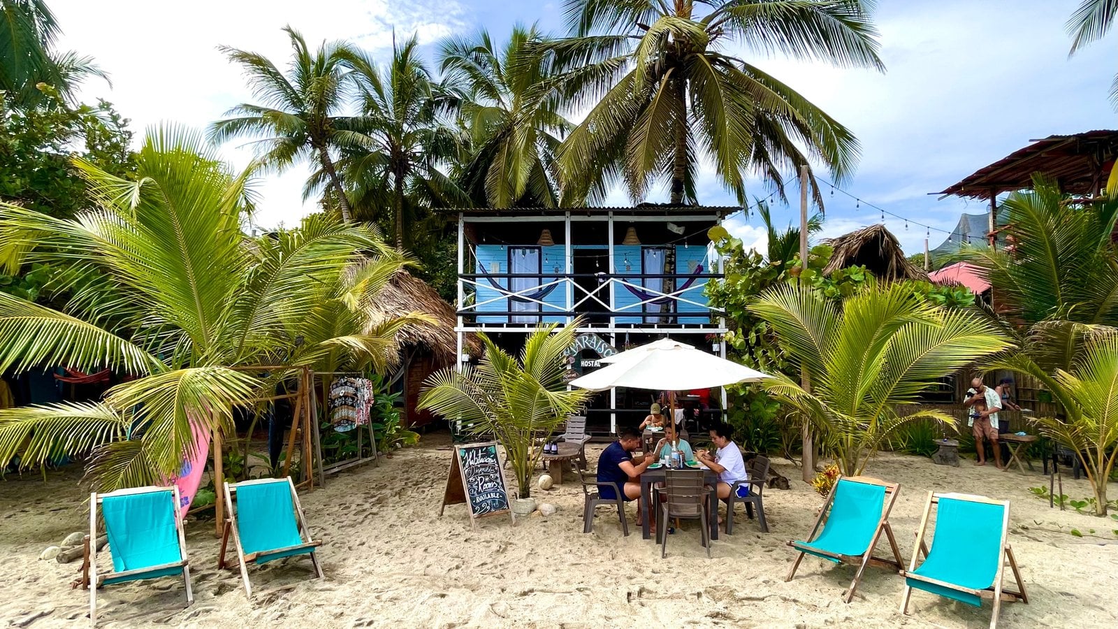 Fachada del Eco Hostal Paraíso sobre la playa Mendihuaca, con palmeras y sillas de playa